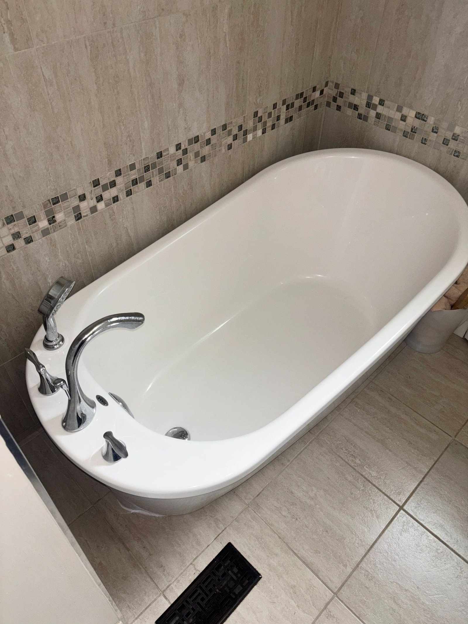 Oval freestanding tub with tiled mosaic border