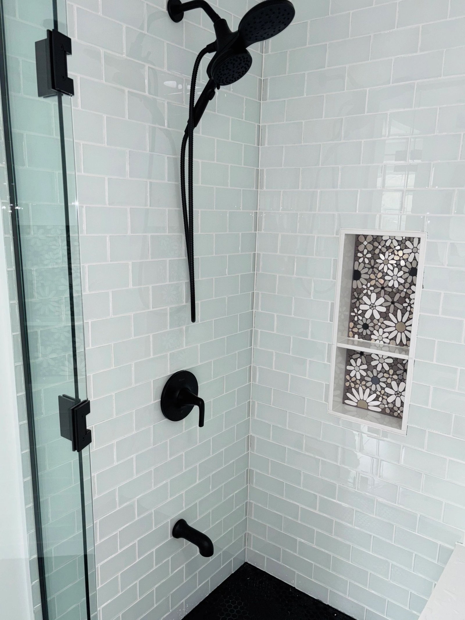 Tiled walk-in shower with black fixtures